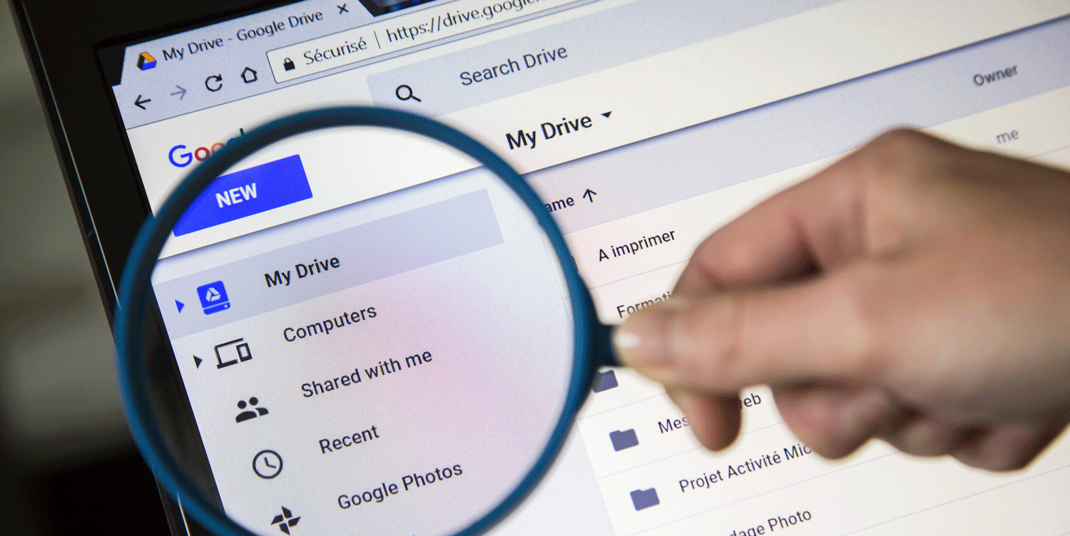 person holding magnifying glass up to laptop